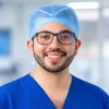 Médico sonriente con uniforme quirúrgico azul y gorro