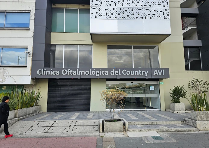 Entrada principal de la Clínica Oftalmológica del Country AVI con letrero visible y una persona caminando al frente