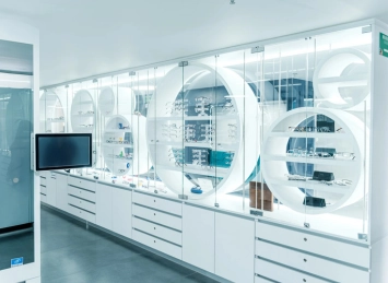 Interior de la Clínica AVI con vitrinas circulares exhibiendo equipos médicos y una pantalla apagada