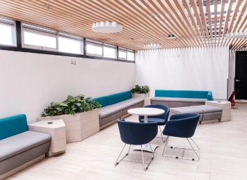 Sala de espera moderna en la Clínica AVI con sofás azules, mesas redondas y plantas decorativas