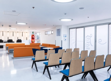 Sala de espera en Instalaciones Clínica AVI con sillas de madera y sofás naranjas